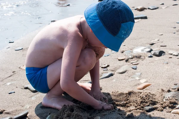 El chico juega a la arena en la costa — Foto de Stock