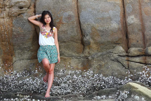 Beautiful young woman posing on stones near sea — Stock Photo, Image