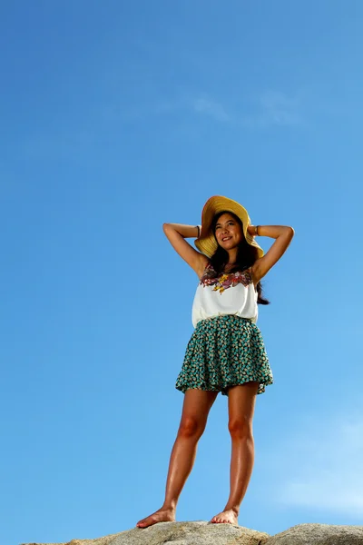 Schöne Frau posiert auf Stein mit blauem Himmel Hintergrund — Stockfoto