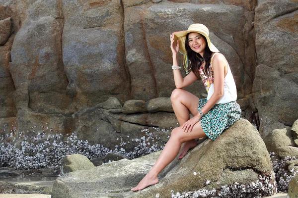 Beautiful young woman posing on stones near beach — Stock Photo, Image