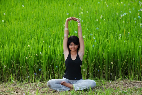 Flicka som utövar yoga i risfält — Stockfoto