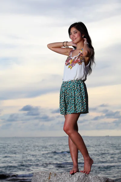 Bella giovane donna in posa su pietre vicino al mare — Foto Stock