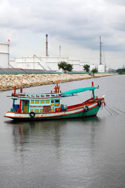 Wooden fishing boat near crude oil tank terminal — Stock Photo, Image