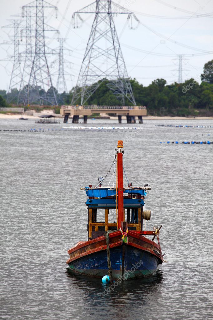 Wooden fishing boat and electrical tower in industrial area