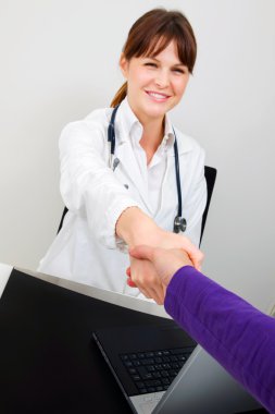 Young caucasian woman doctor and patient shake hands clipart