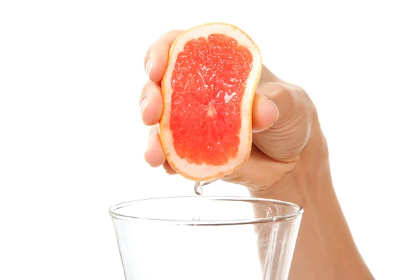 Hand squeezing red orange or grapefruit juice — Stock Photo, Image