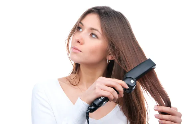 Brunette woman using hair straighteners black flat iron to make — Stock Photo, Image
