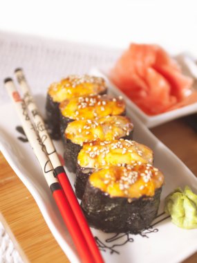 Hot sushi on plate with chopsticks clipart