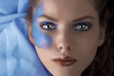 Face shot of a laying model with blue glitter make up clipart