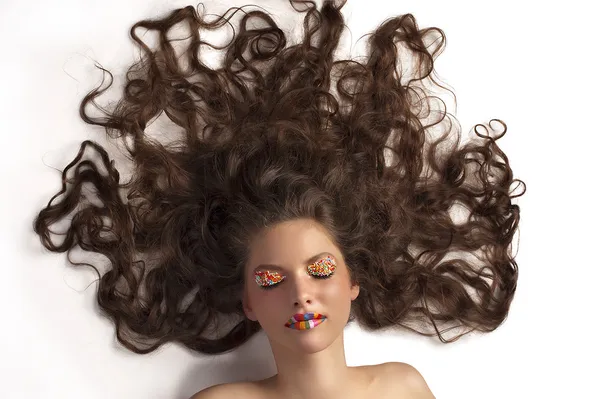 Leuk meisje met gekleurde make-up en krullend haar — Stockfoto