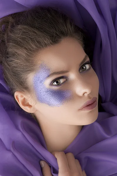 Schot van de schoonheid van een meisje met paarse glitters make-up leggen tussen — Stockfoto