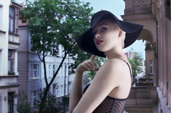 Jovem loira mulher da moda em chapéu preto elegante em backgro urbano — Fotografia de Stock