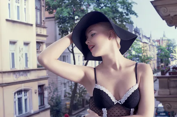 Módní záběr blondýnka s kloboukem a staré město — Stock fotografie