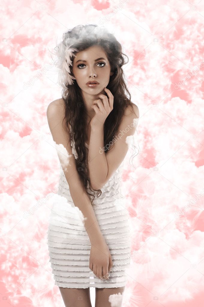 Posing model wearing white dress and soft pink featheron white