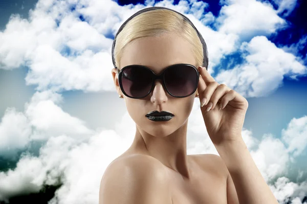 Fashion shot of blond girl with sunglasses looking at the camera — Stock Photo, Image