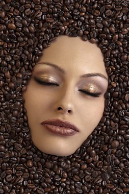 Girl's face immersed in coffee beans clipart