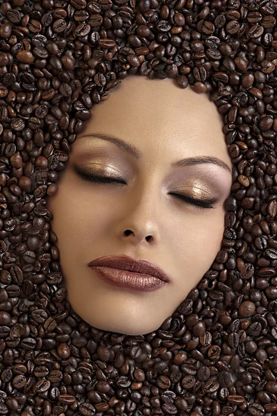Лицо девушки, погруженное в кофейные зерна — стоковое фото