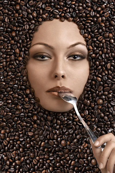 Cara de una hermosa chica inmersa en granos de café — Foto de Stock
