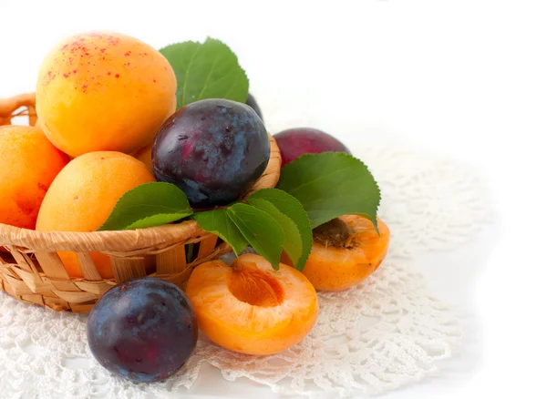 Fresh apricots and plums in a basket — Stock Photo, Image