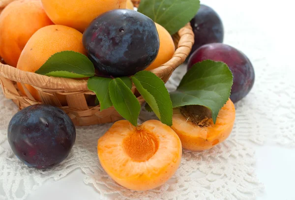 Verse abrikozen en pruimen in een mand — Stockfoto