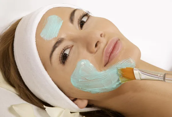 Giovane donna ottenere bellezza trattamento maschera di pelle sul suo viso con — Foto Stock