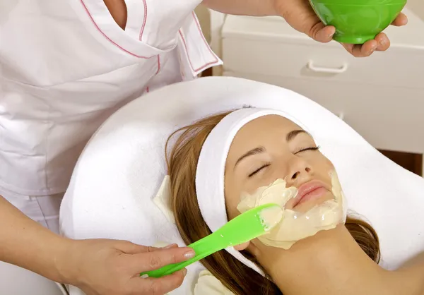 Νεαρή γυναίκα να πάρει ομορφιά δέρμα θεραπεία μάσκα στο πρόσωπό της με Εικόνα Αρχείου