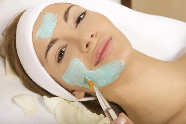 Junge Frau bekommt Schönheitsmaske Behandlung auf ihrem Gesicht mit — Stockfoto