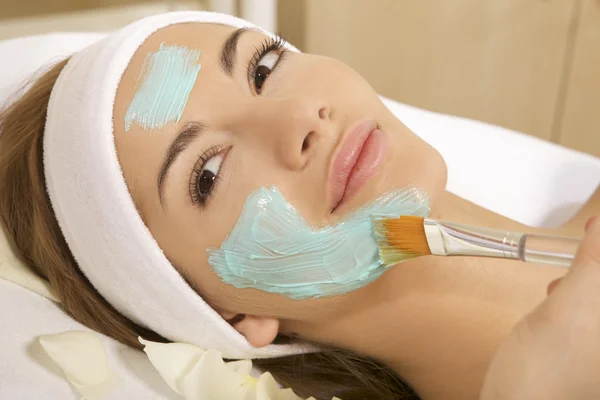 Genç bir kadın ile yüzünde güzellik cilt maskesi tedavi görüyor — Stok fotoğraf