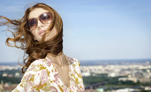 Mooi meisje in zonnebril op achtergrond blauwe hemel — Stockfoto