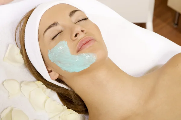 Junge Frau bekommt Schönheitsmaske Behandlung auf ihrem Gesicht mit — Stockfoto