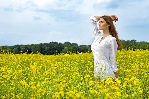 Брюнетка жінка в полі жовті квіти — стокове фото