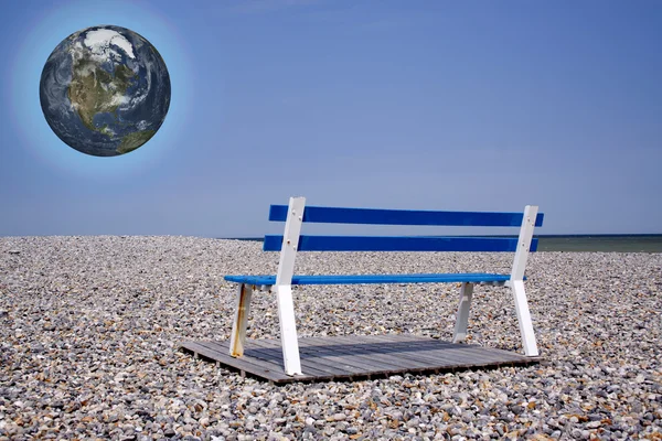 Planet earth above Beach-chair on flintstone along the coast — Stock Photo, Image