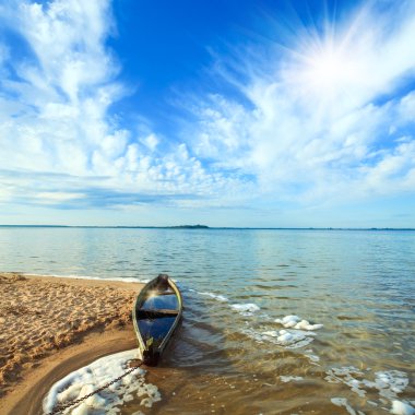 Old flooding boat on summer lake shore clipart