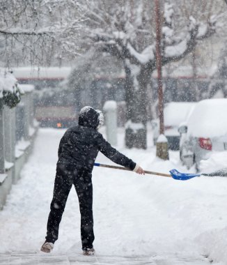 Woman shoveling snow from a sidewalk after a heavy snowfall in a clipart