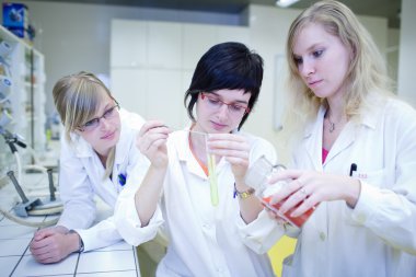 thre kadın araştırmacılar bir kimya laboratuarında araştırma yürütmektedir
