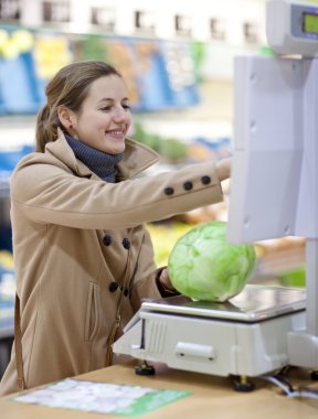 Beautiful young woman shopping for fruits and vegetables in prod clipart