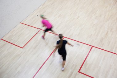 Two female squash players in fast action on a squash court (moti clipart