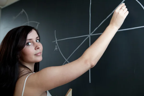 Hübsche junge Lehrerin zeichnet auf der Tafel / Tafel während — Stockfoto