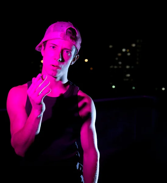 Knappe jongeman verlicht met kleurrijke verlichting permanent op een dak een — Stockfoto