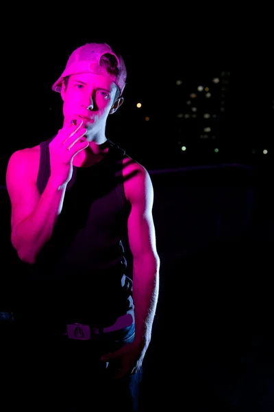 Przystojny młody mężczyzna zapalił z kolorowymi światłami stojąc na dachu — Zdjęcie stockowe