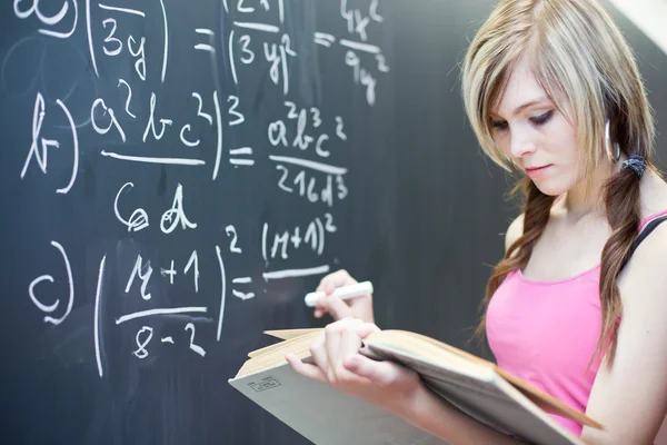 Hübsche junge Studentin, die auf der Tafel / Tafel schreibt — Stockfoto