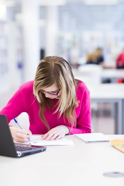 stock image In the library - pretty, female student with laptop and books wo