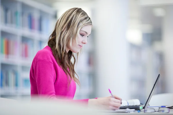 Dans la bibliothèque - jolie étudiante avec ordinateur portable et livres wo — Photo