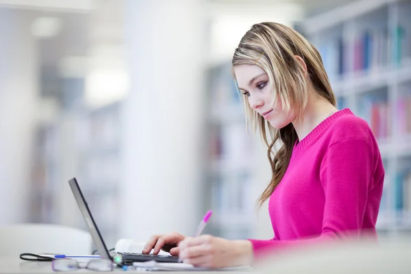 In de bibliotheek - mooie, vrouwelijke student met laptop en boeken wo — Stockfoto