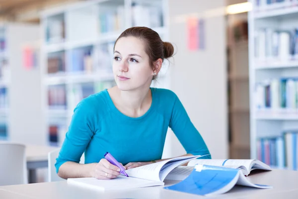 Pretty young college student in a library (shallow DOF; color to — Stock Photo, Image