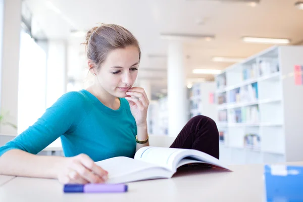 Pretty young college student in a library (shallow DOF; color to — Stock Photo, Image