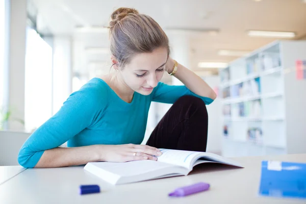 Bir kütüphanede oldukça genç bir üniversite öğrencisi (sığ serbestlik; renk — Stok fotoğraf