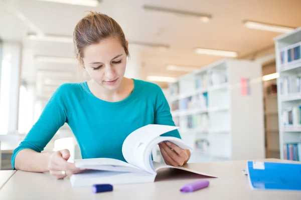 Estudante universitário muito jovem em uma biblioteca (DOF rasa; cor para — Fotografia de Stock