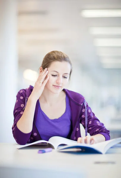 Estudiante universitario bastante joven en una biblioteca (DOF poco profundo; color a — Foto de Stock