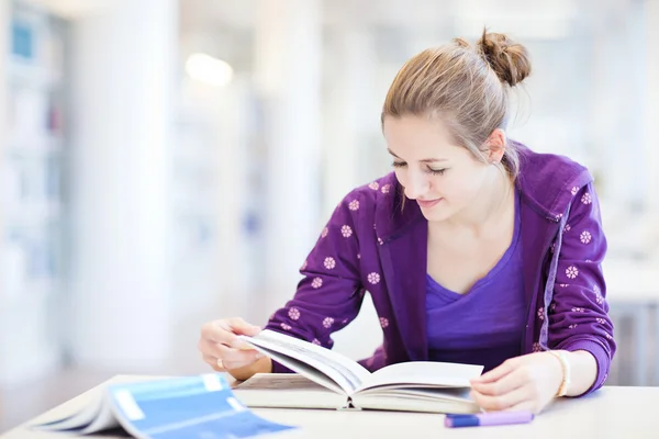 Estudante universitário muito jovem em uma biblioteca (DOF rasa; cor para — Fotografia de Stock